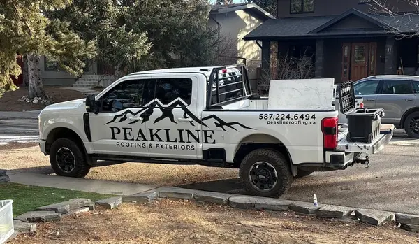 Peakline Roofing & Exteriors branded company truck at a Calgary jobsite