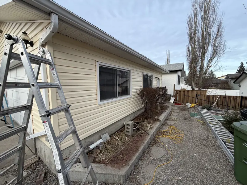 Calgary home exterior with ladder set up for siding and eavestrough work by Peakline Roofing & Exteriors