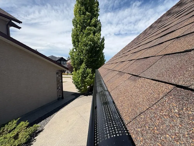 Complete gutter replacement by Peakline Roofing & Exteriors featuring seamless aluminum gutters and downspouts for optimal water management in Calgary