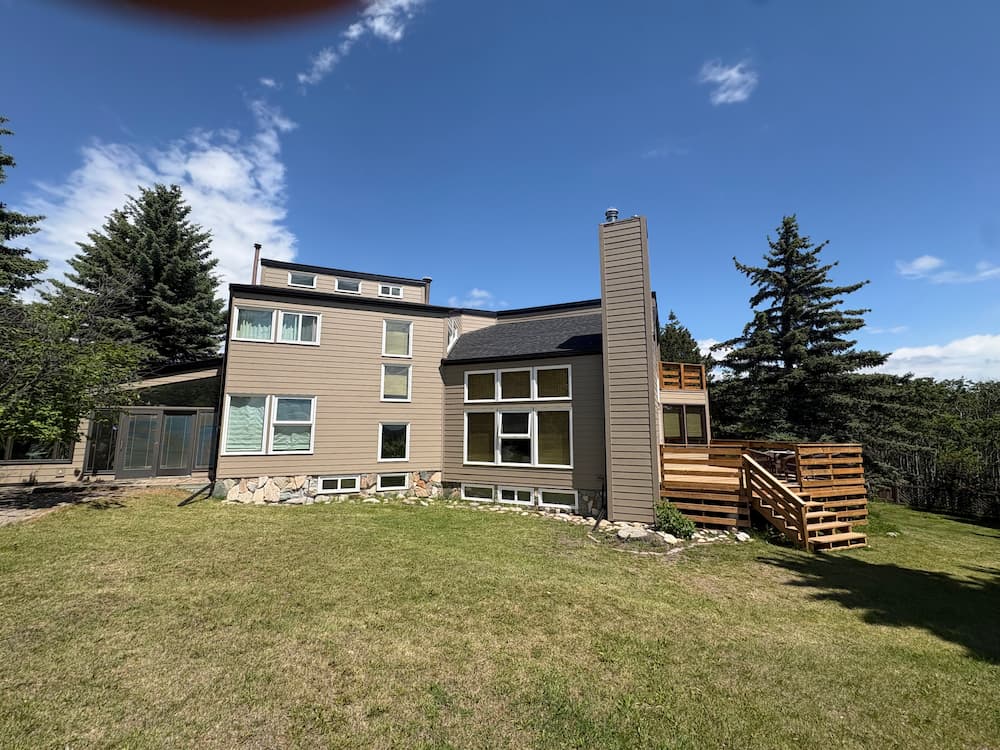 Completed James Hardie fiber cement lap siding with new trim and stone detail on a Calgary home by Peakline Roofing